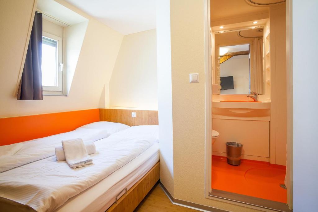 una piccola camera da letto con un letto e uno specchio di easyHotel Basel - self service and self check-in a Basilea