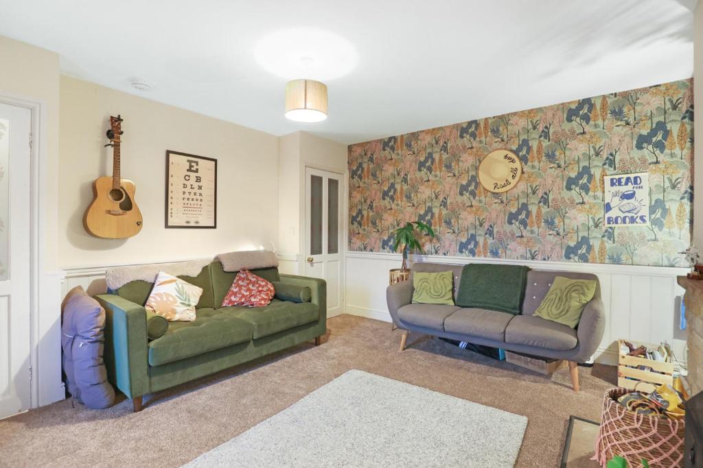 Woodside Cottage - North East Escapes في أوتيربيرن: غرفة معيشة مع كنبتين وجيتار
