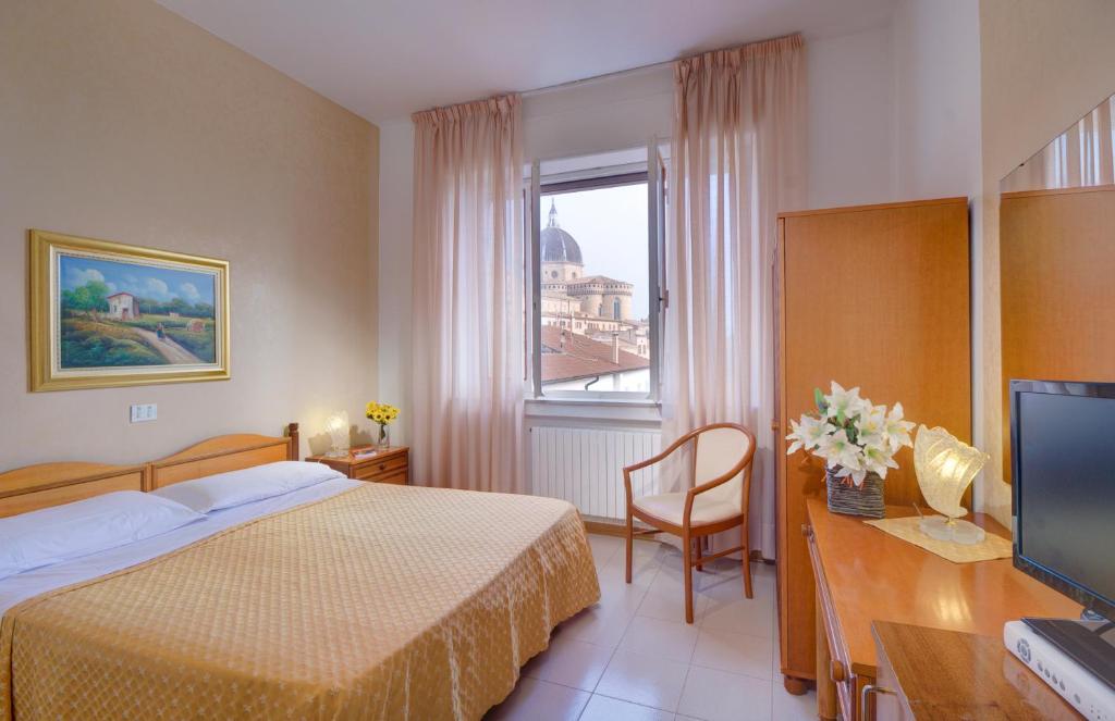 a hotel room with a bed and a desk with a television at San Gabriele in Loreto
