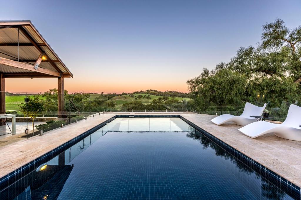 a swimming pool with white chairs and a house at Gawler Park Estate in Angaston