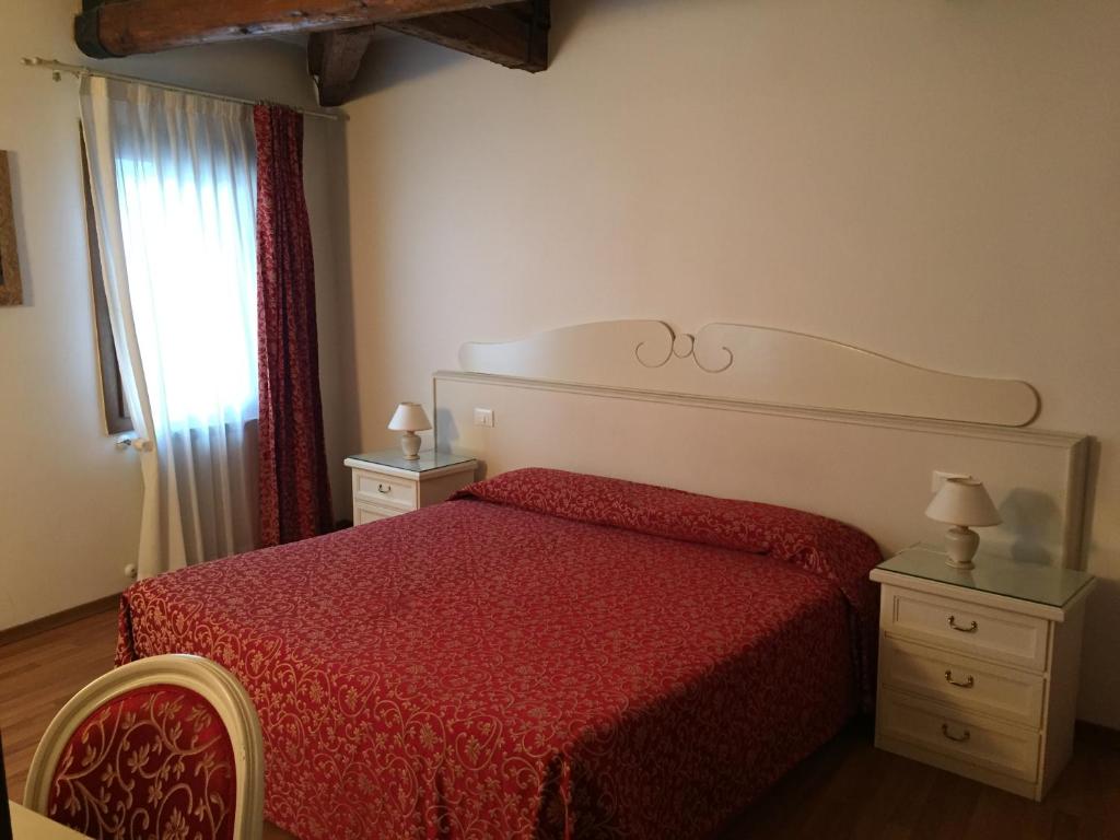 a bedroom with a bed with a red bedspread and a window at Venice Resorts in Venice