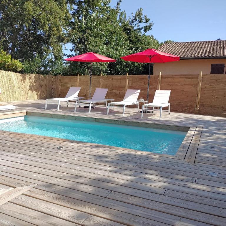 - une piscine avec des chaises blanches et des parasols rouges dans l'établissement Maison Peonia, à La Teste-de-Buch