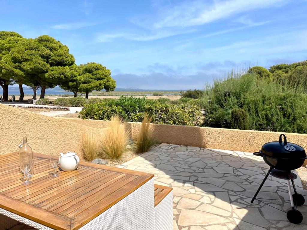 d'une terrasse avec un barbecue et une table en bois. dans l'établissement Maison 5 pers - vue étang - nature - piscine, à Fitou