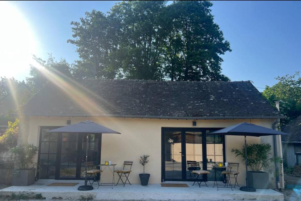 a house with tables and umbrellas in front of it at Chambre indépendante proche du Circuit des 24h et du Pôle Européen du Cheval in Yvré-lʼÉvêque