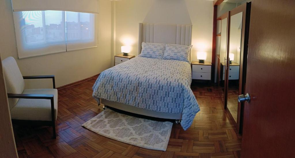 Un dormitorio con una cama y una ventana y una silla. en La Palmera, en Lima