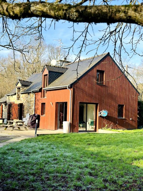 une grande grange rouge avec un bâtiment dans l'établissement La Lande d'Ouée - Sauna & Convivialité, à Saint-Aubin-du-Cormier