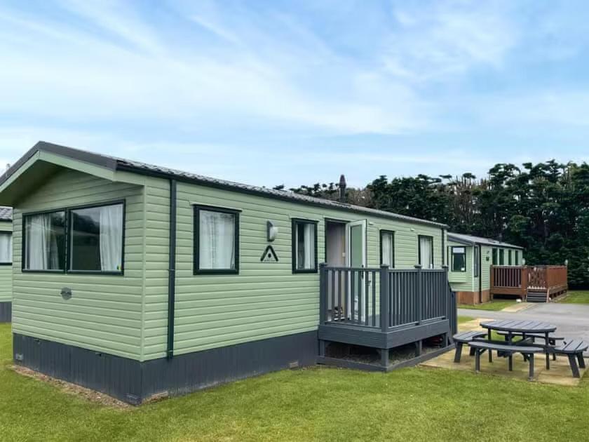 una casa verde con mesa de picnic y banco en Holiday Home by the river Nidd 6, en Knaresborough