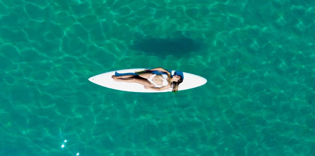 une femme allongée sur une planche de surf dans l'eau dans l'établissement Villaggio Camping Poseidon - Bungalows & Rooms with Sea View in Nature, à Santa Caterina Dello Ionio Marina
