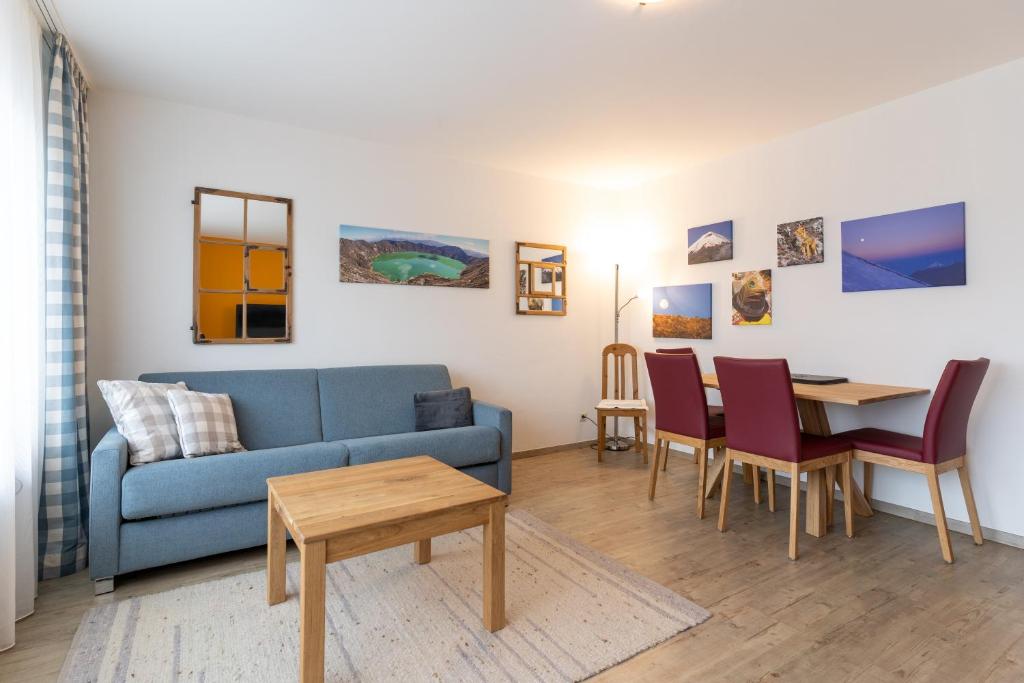 Una sala de estar con un sofá azul y una mesa. en Ferienwohnung Altamirano, en Oberstdorf