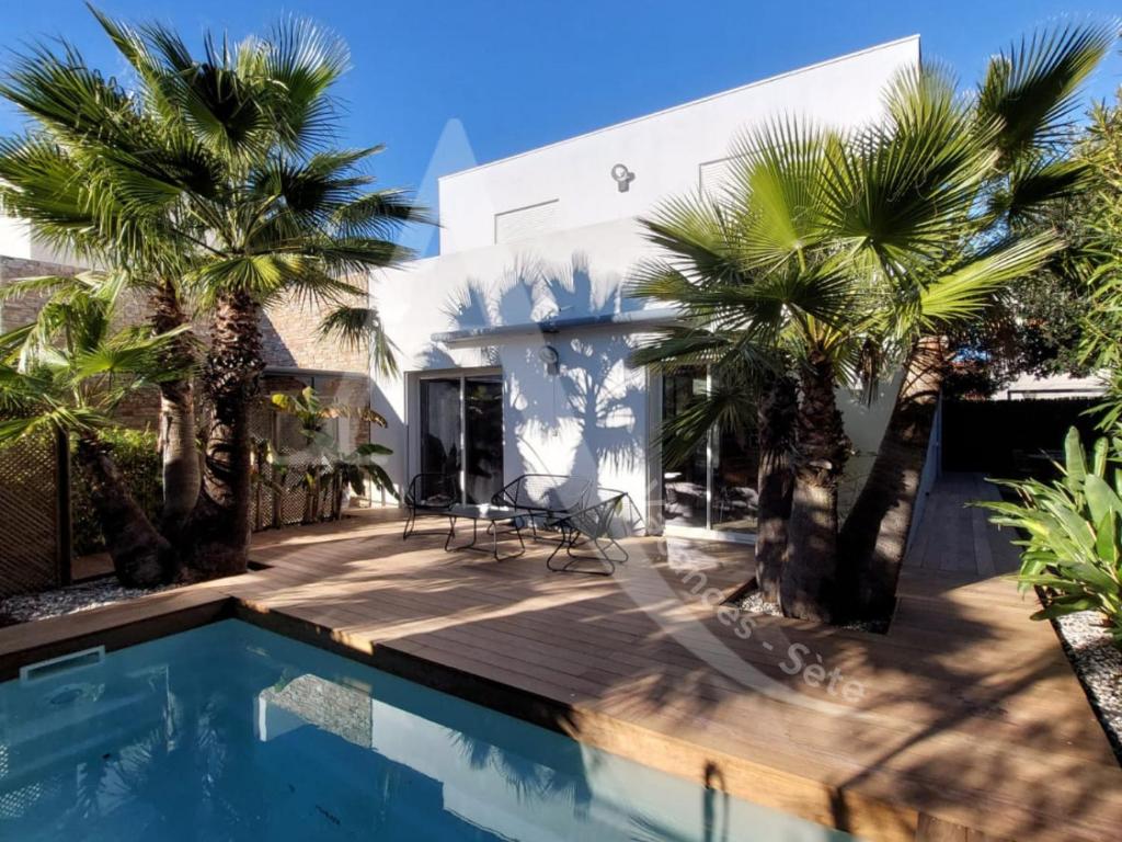 une maison avec une piscine et des palmiers dans l'établissement Super villa 6 personnes avec piscine et climatisation a cote des plages, à Sète