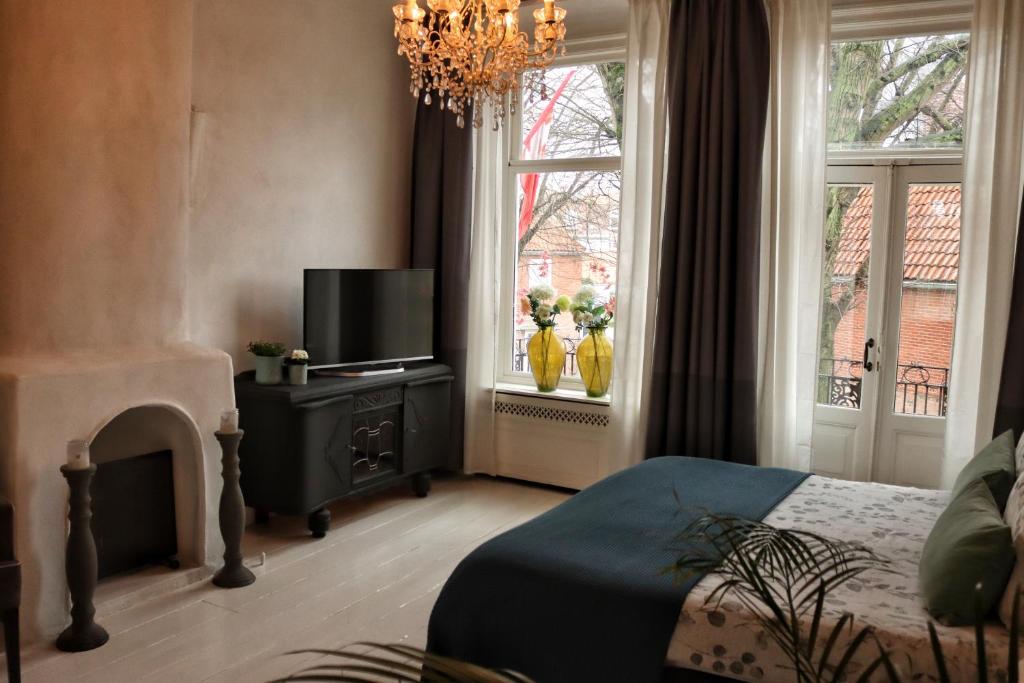 a bedroom with a bed and a tv and windows at Appartement Zeeuws genoegen in Vlissingen