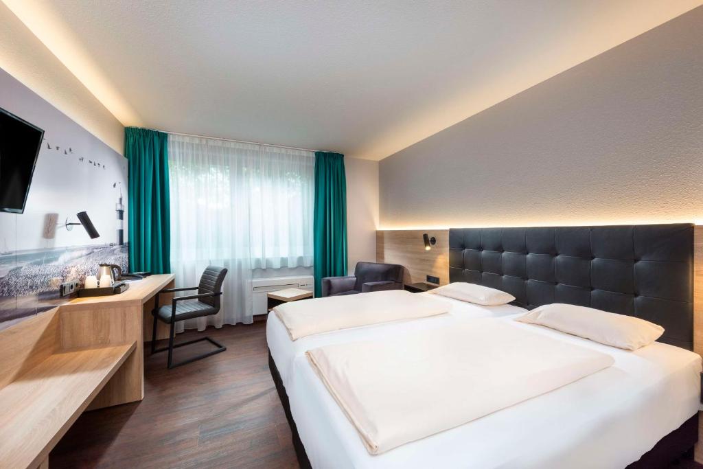 a hotel room with a large bed and a desk at Best Western Hotel Achim Bremen in Bremen