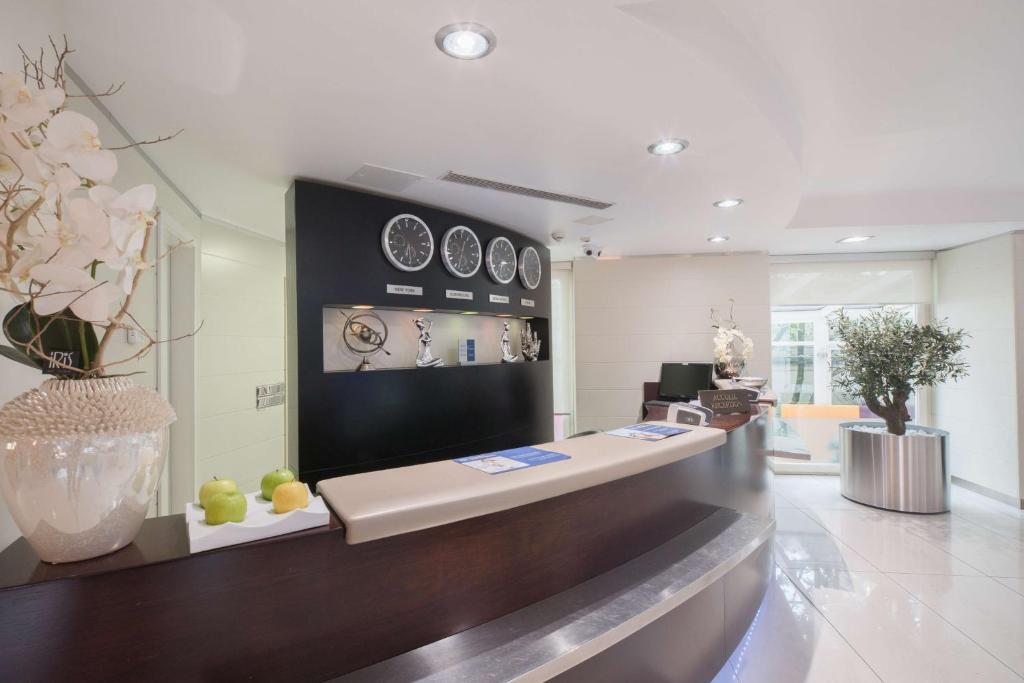 a lobby with a counter with clocks on the wall at Best Western Plus Grand Hotel Victor Hugo in Luxembourg