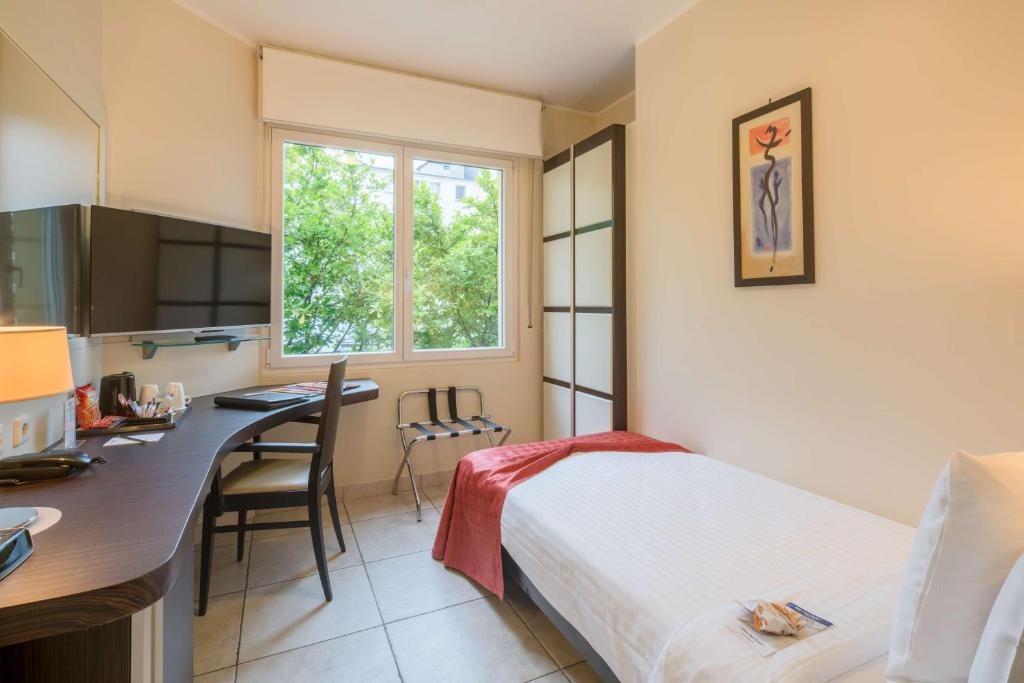 a bedroom with a bed and a desk and a kitchen at Best Western Plus Grand Hotel Victor Hugo in Luxembourg