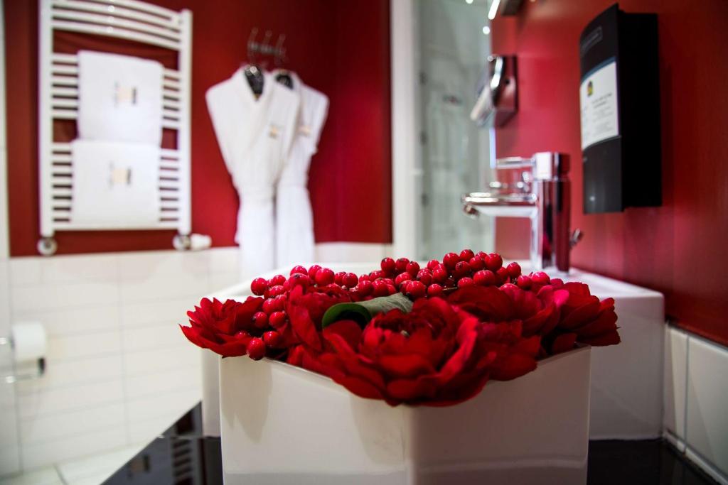 a bouquet of red flowers on a counter in a bathroom at Best Western Plus Grand Hotel Victor Hugo in Luxembourg