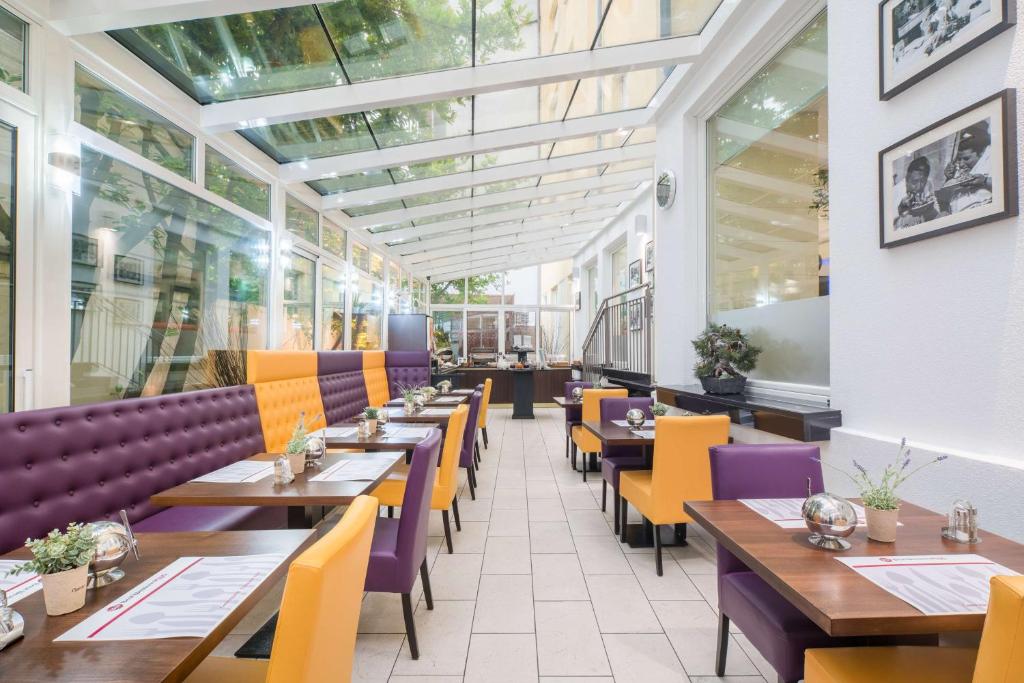a restaurant with wooden tables and purple and yellow chairs at Best Western Plus Grand Hotel Victor Hugo in Luxembourg