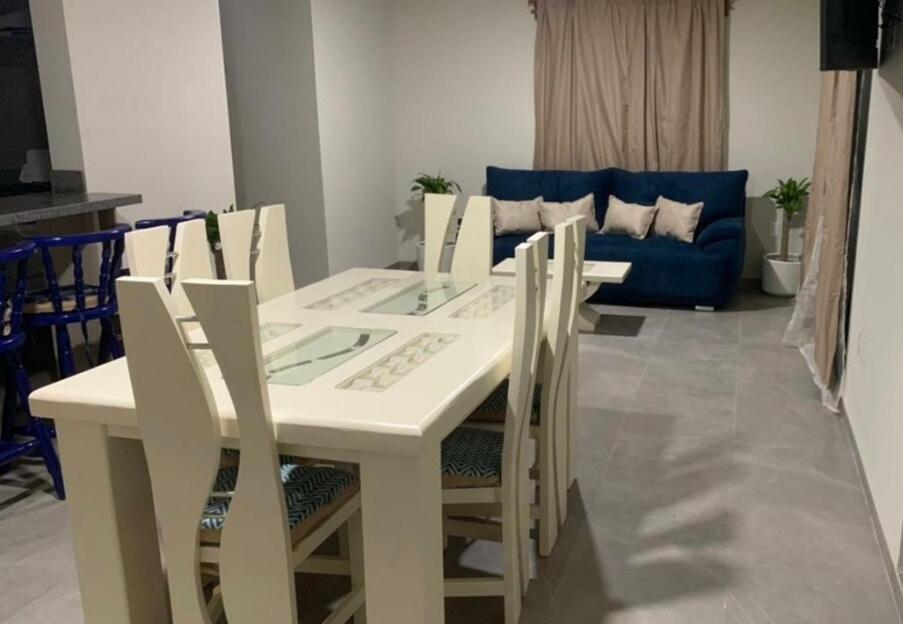 a white dining room table and chairs with a blue couch at Amplio Depa in San Luis Potosí