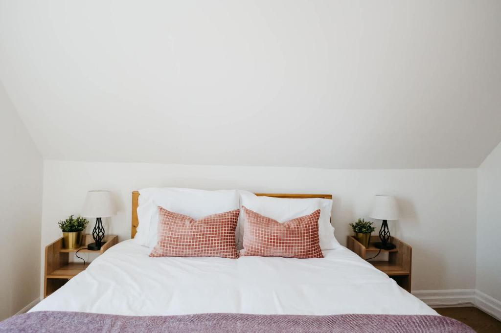 a bedroom with a white bed with pink pillows at Park and Mill - Hot Tub and Bocce Court in Bloomfield