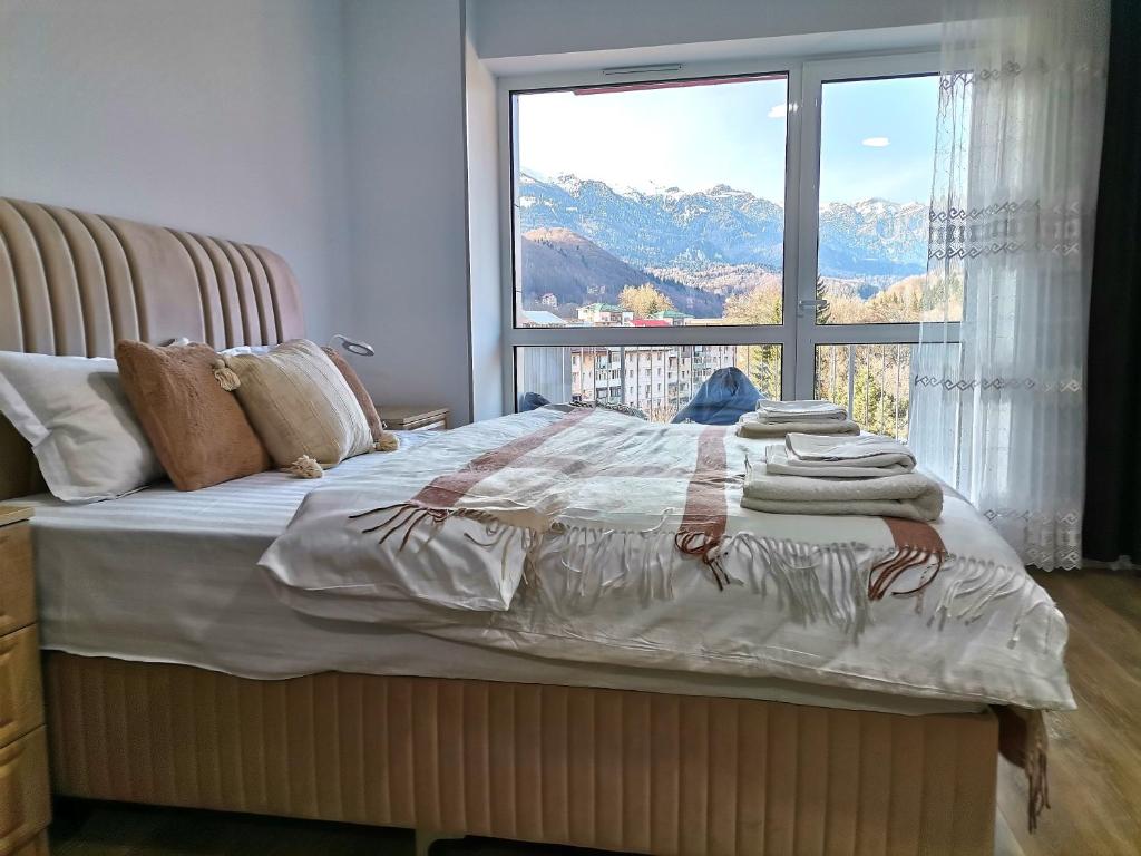 a bedroom with a bed with a large window at Tutu Studio Sinaia cu vedere panoramica Early Checkin in Sinaia