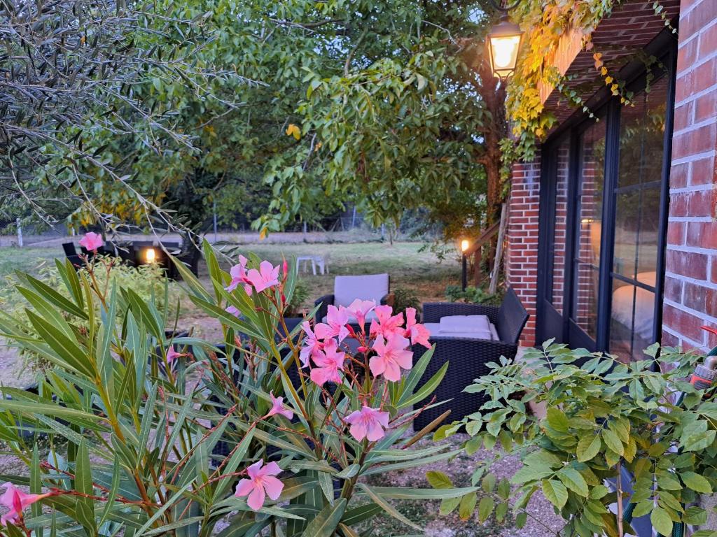 - un jardin avec des fleurs roses et des chaises sur la terrasse dans l'établissement Les gîtes de Saint-ange, à Pezou