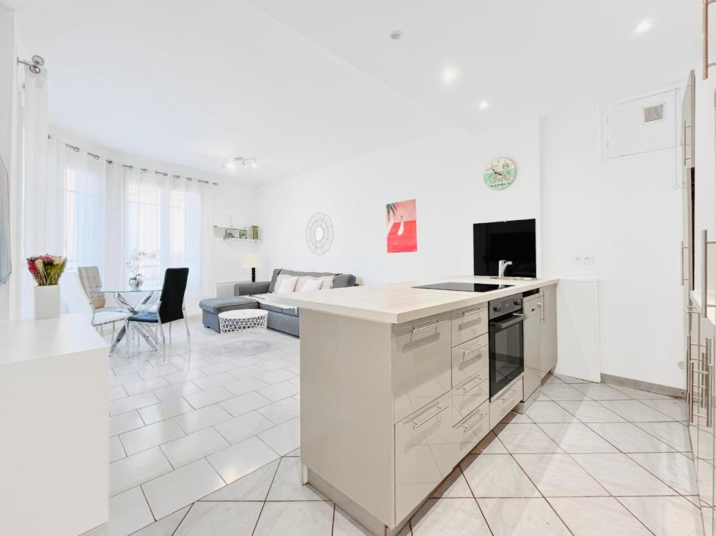Il comprend une cuisine blanche avec un évier et un salon. dans l'établissement Le Germain - Logement 3 pièces, à Cannes