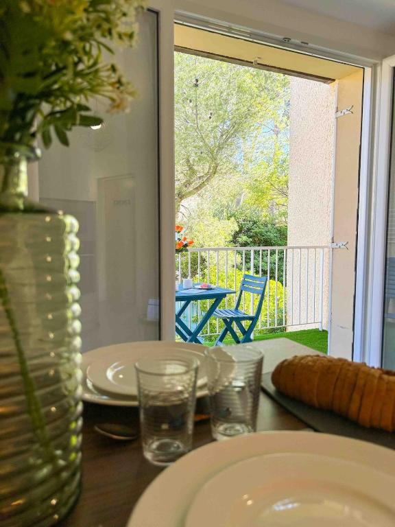 une table avec des assiettes, des verres et un vase sur une table dans l'établissement T2 - accès plage - balcon et parking privé, à Sanary-sur-Mer