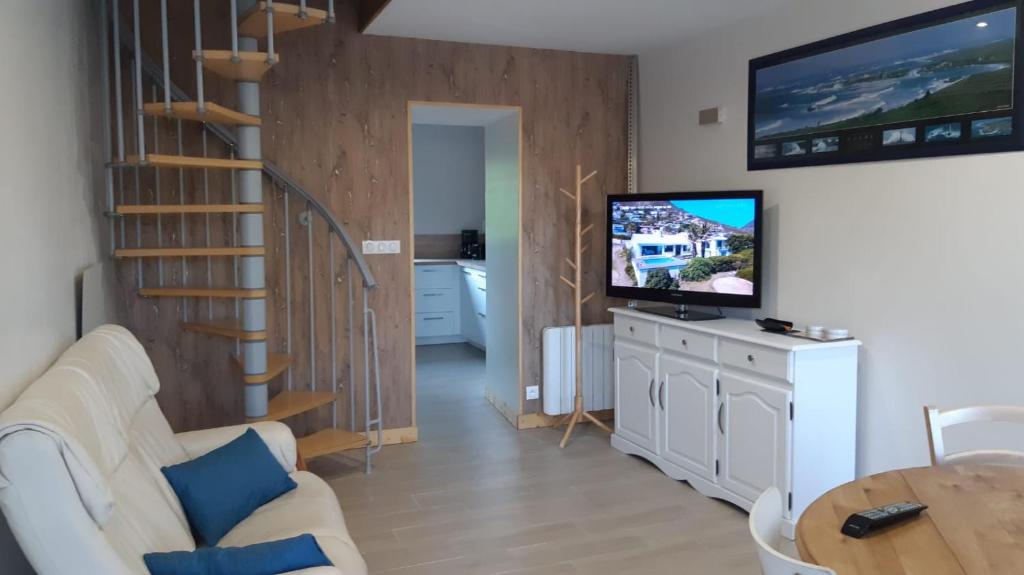 un salon avec un canapé blanc et une télévision dans l'établissement Le BOTELLA, à Teurthéville-Hague