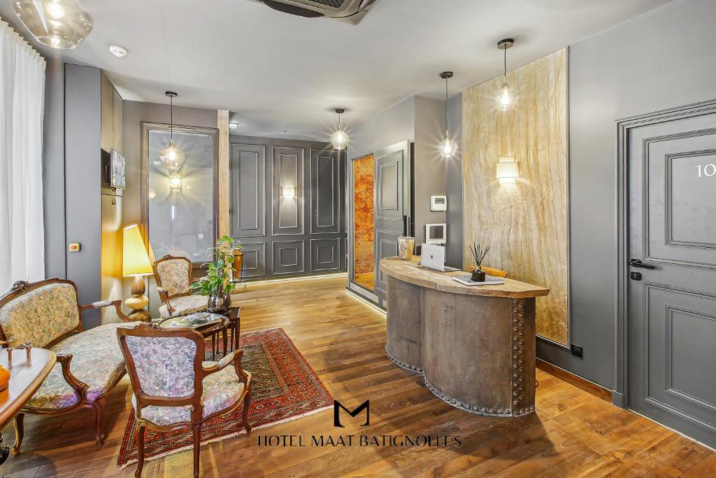 un salon avec une table et des chaises dans l'établissement Hôtel Maât Batignolles, à Paris