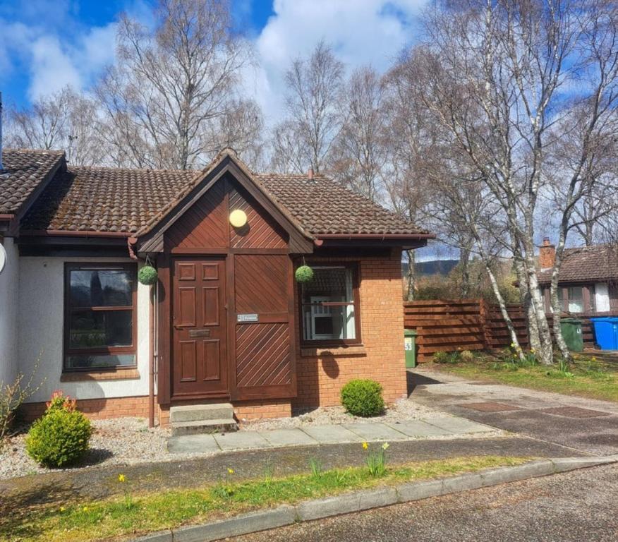 a small house with a brown door at Steam Train Cottage in Aviemore