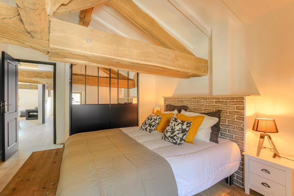 a bedroom with a bed and a brick wall at L'élégance aux Ponts Tarrets in Légny