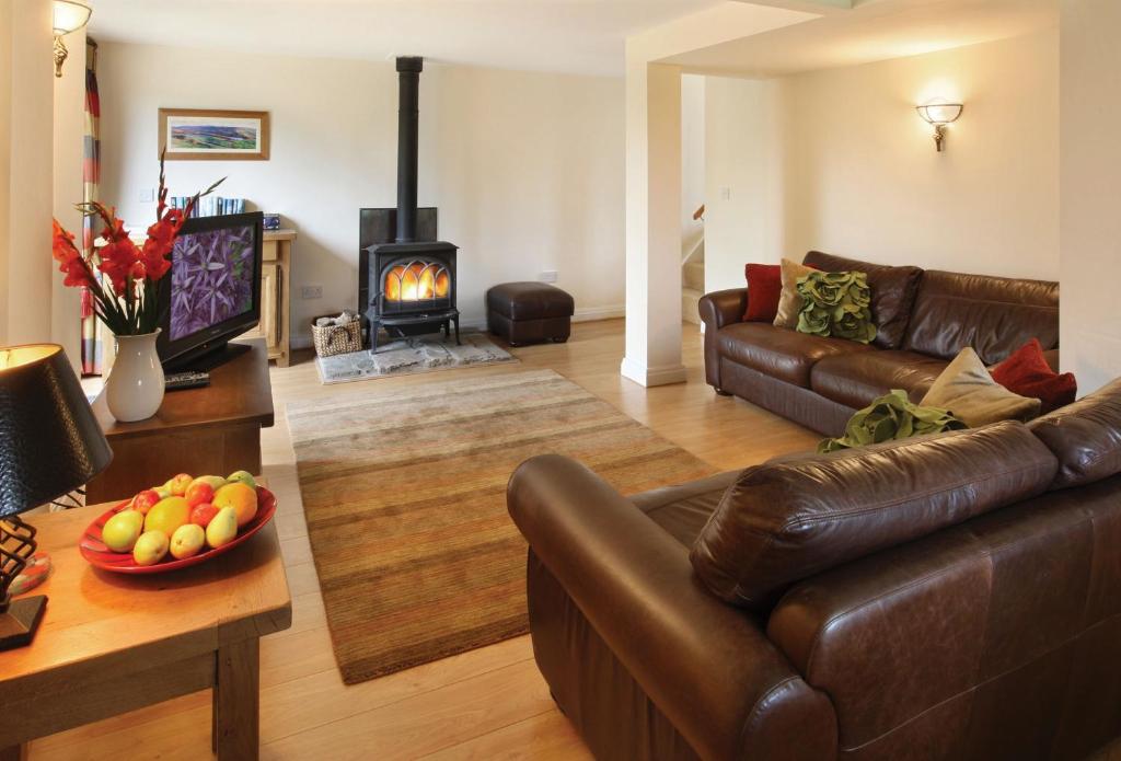ein Wohnzimmer mit einem Ledersofa und einem Kamin in der Unterkunft Orchard Cottage Cheshire in Rainow