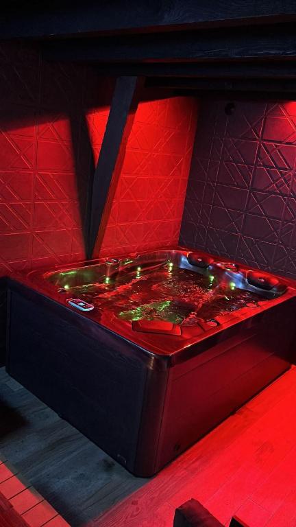 une chambre rouge avec un bain à remous éclairé dans l'établissement Love Room Spa - Sauna - Hammam, à Domérat