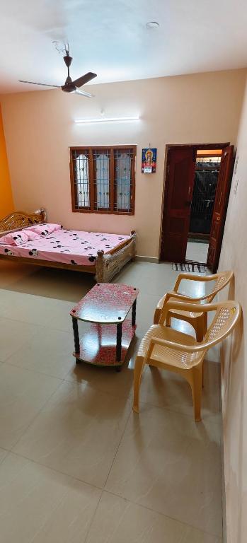 a room with two beds and a table and chairs at Sri Annai Home Stay I in Tiruvannāmalai