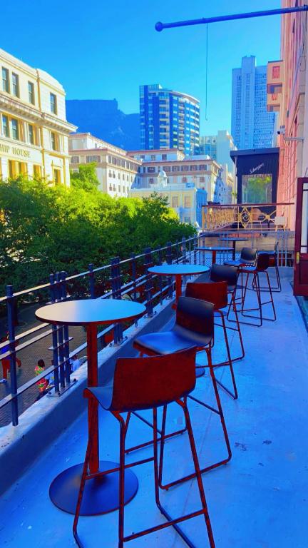a row of tables and chairs sitting on a balcony at Drame MC Good Night Lodge in Cape Town