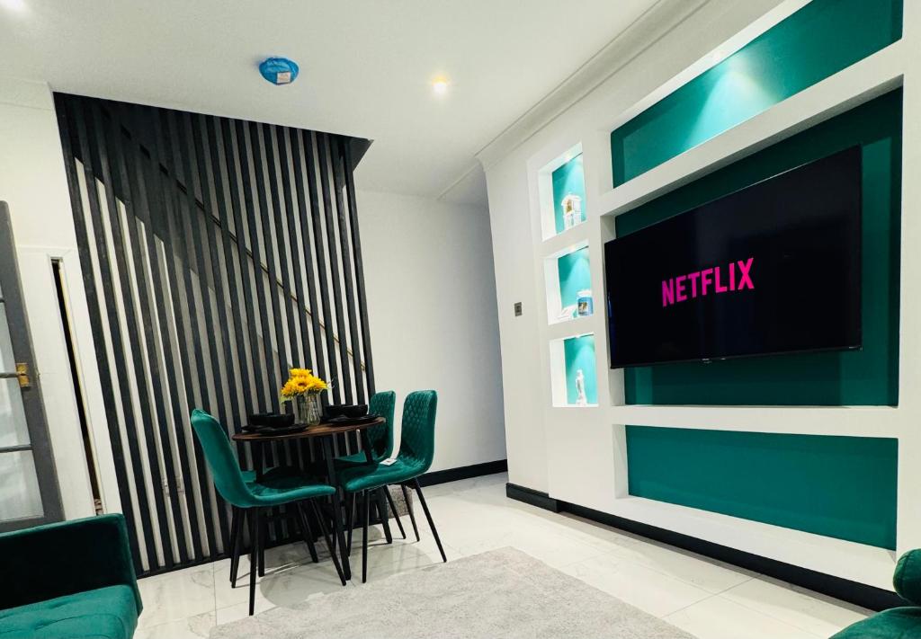 ein Esszimmer mit einem TV und einem Tisch mit Stühlen in der Unterkunft Your Home Away, Luxury House in Swansea