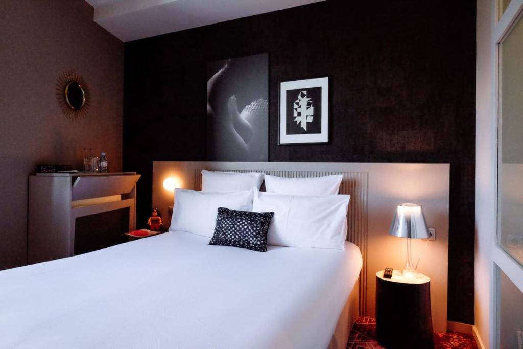 a bedroom with a large bed with white pillows at Hôtel des Beaux-Arts Toulouse in Toulouse