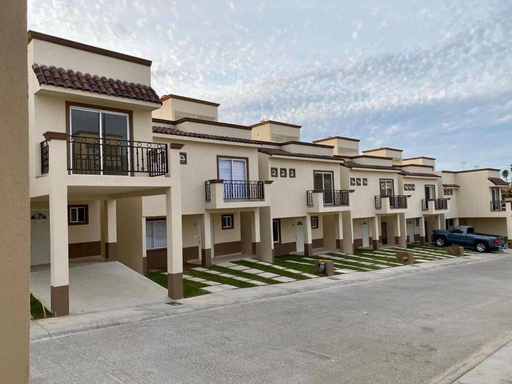 eine Reihe von Apartmentgebäuden mit einem Auto vor dem Haus in der Unterkunft Brisas Del Mar Villa 3 BR 2 BA with pool in Tijuana
