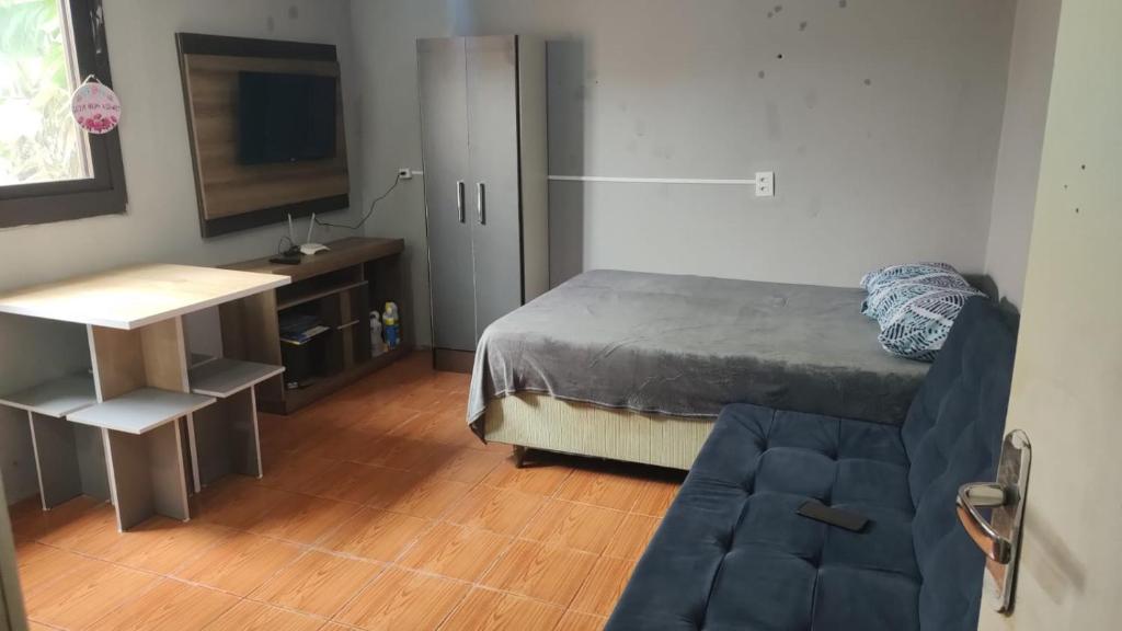 une chambre avec un lit, une télévision et un canapé dans l'établissement Kitnet geminada próximo da praia, à Torres