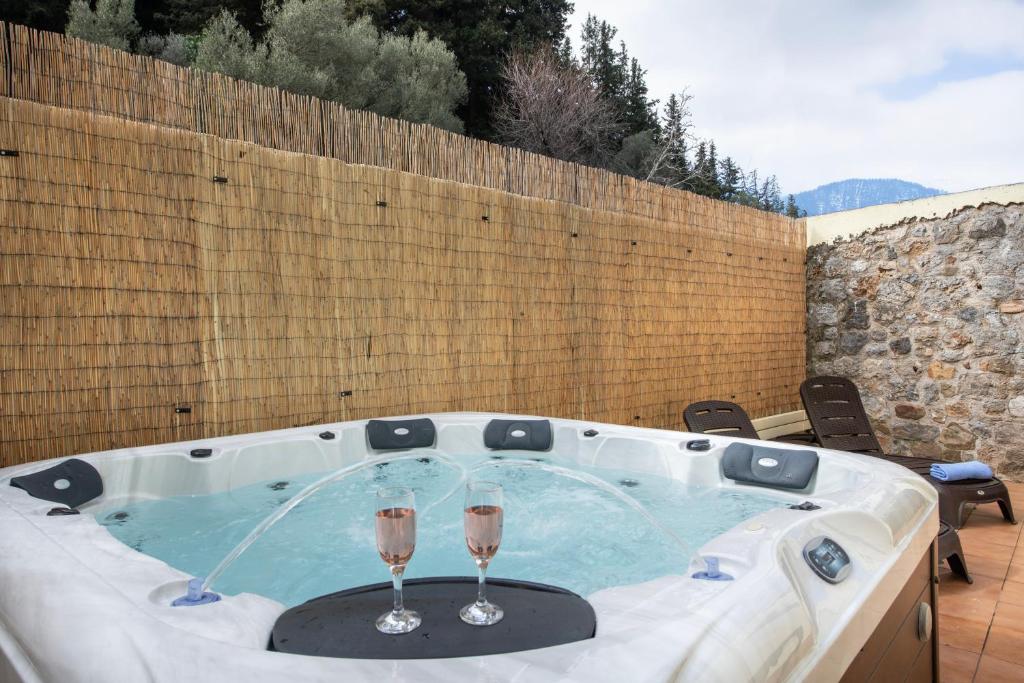 a hot tub with two wine glasses in it at Jacuzzi Villa Nena in Thérison
