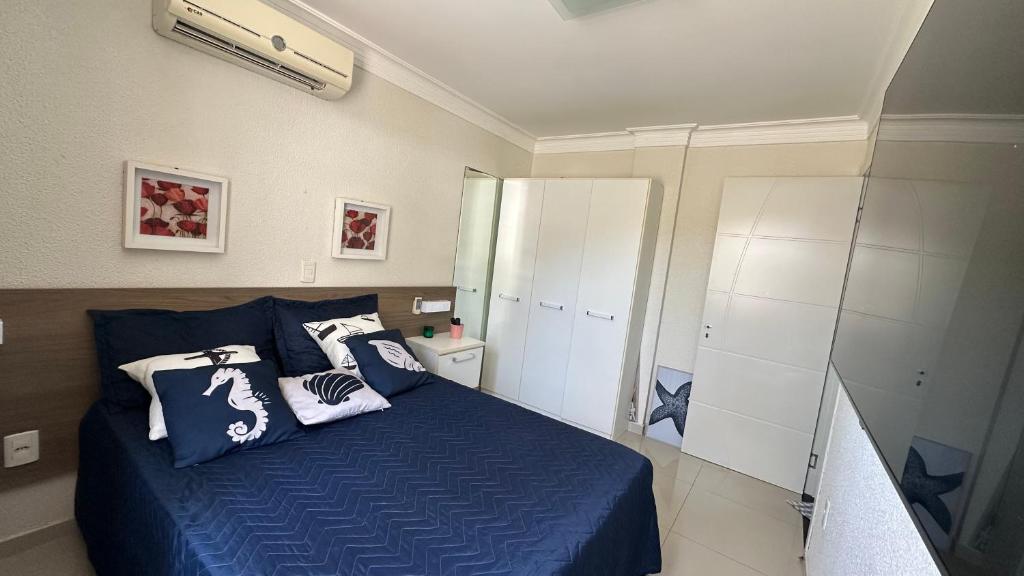 a bedroom with a blue bed with pillows on it at Bombinhas Summer Beach - Praia de Bombas apartamento in Bombinhas