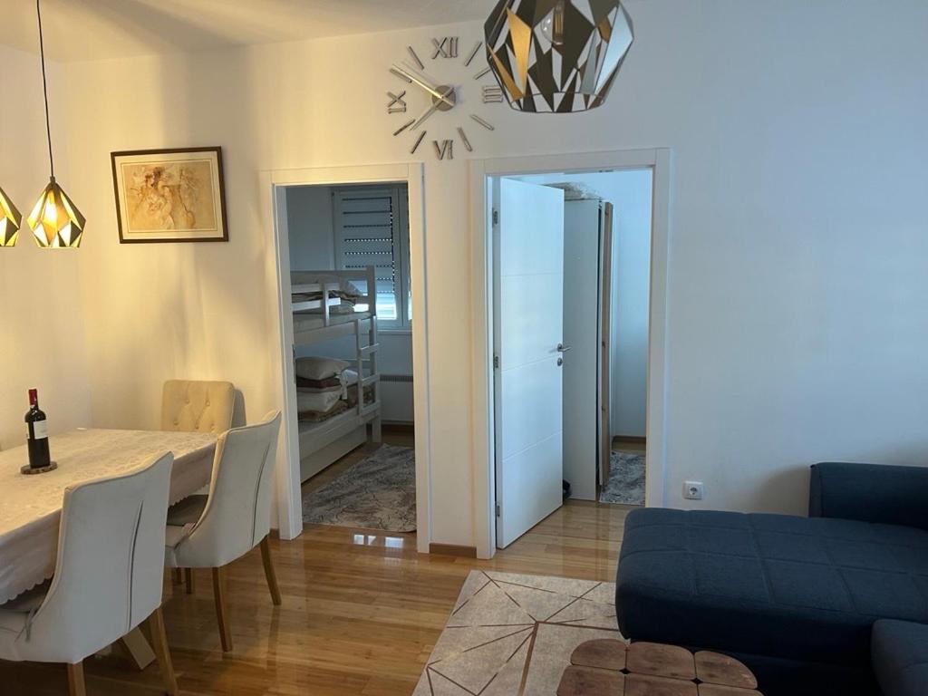a dining room with a table and a clock on the wall at Apartman 10 in Zlatibor