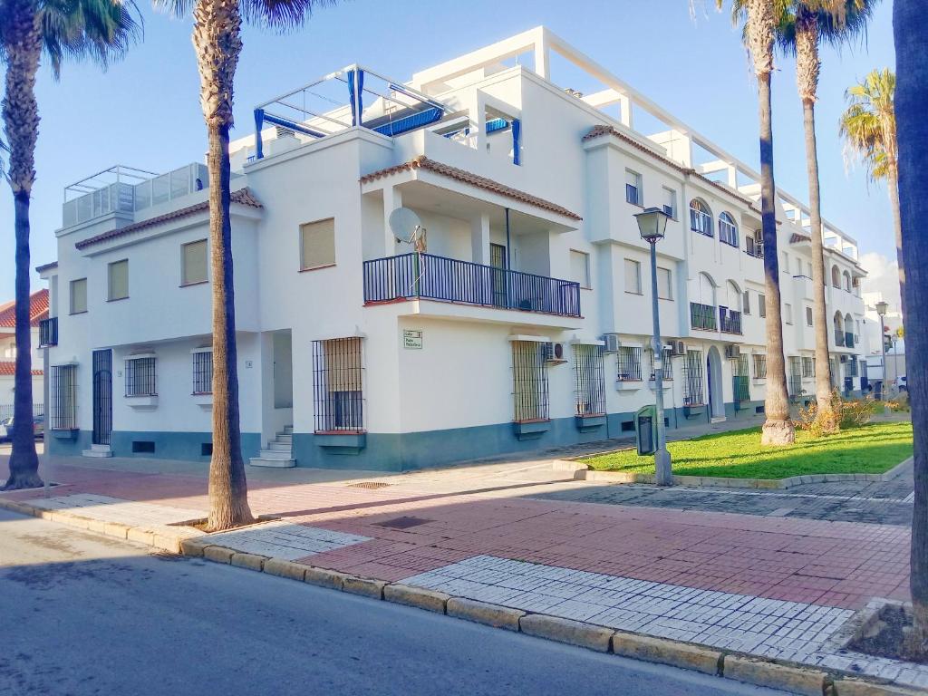 biały budynek z palmami przed nim w obiekcie Top Rota Playa La Costilla Costa de la Luz w mieście Rota