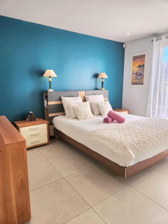 une chambre avec un grand lit avec un mur bleu dans l'établissement Domaine dans les Vignes, à Roquefort-la-Bédoule