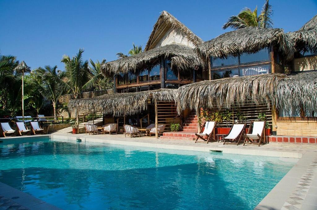 a resort with a swimming pool with chairs and a building at Casitas en Vichayito, a Pasos de la Playa in Los Órganos