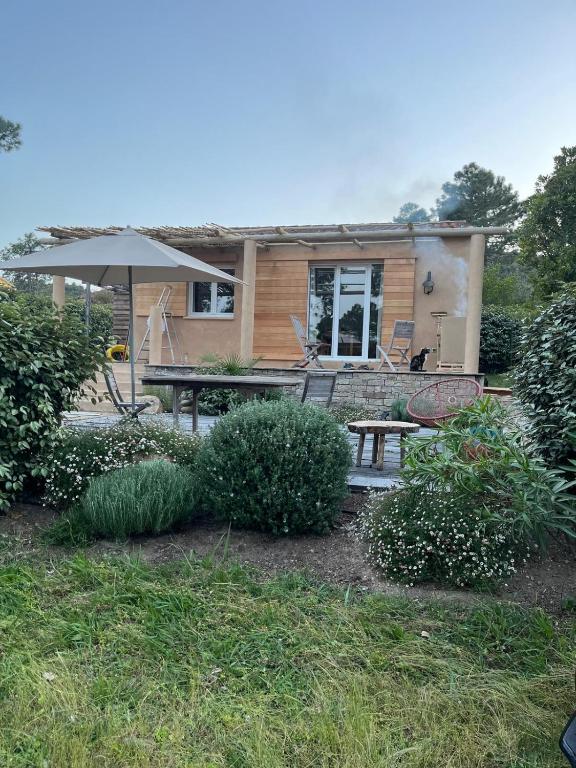 une maison avec une table de pique-nique et un parasol dans l'établissement Pianiccia * Accés plage * proche Porto Vecchio, à Sari-Solenzara