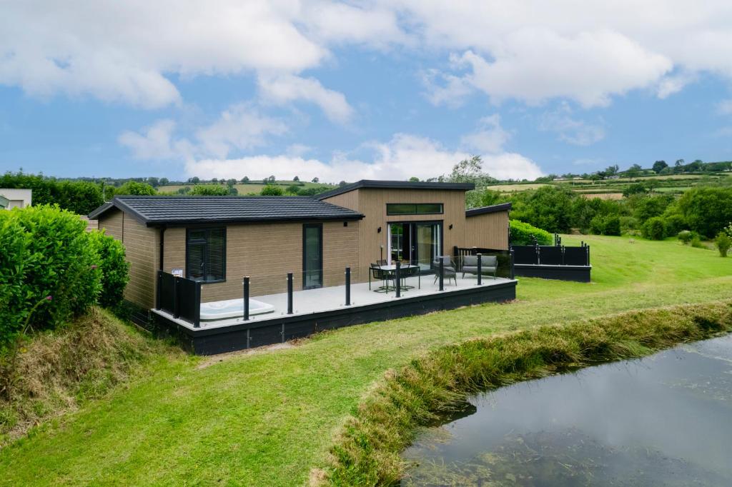 una casa con una gran terraza junto a un río en The Duck Pond - Countryside Hot Tub, en Narberth