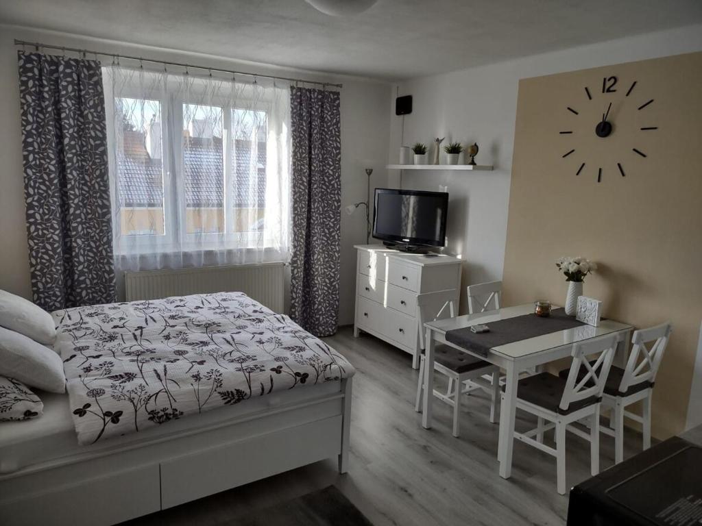 1 dormitorio con cama, mesa y reloj en Útulný byt v centru Kroměříže, en Kroměříž
