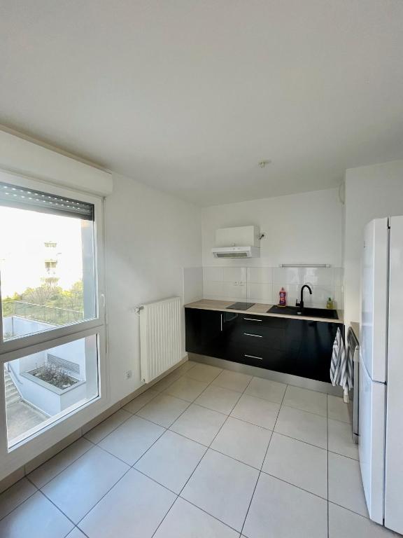 une cuisine blanche avec un réfrigérateur et une fenêtre dans l'établissement T2 Neuf Bordeaux Bassins à Flots, à Bordeaux