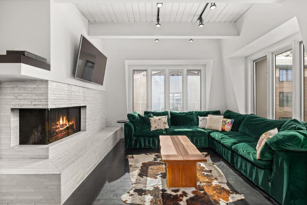 sala de estar con sofá verde y chimenea en Chateau Dumont Unit 21, Fully Renovated Top Floor Condo, Downtown Aspen, Panoramic Mountain Views, en Aspen