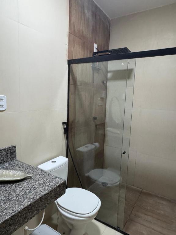 Un baño con inodoro y ducha de cristal. en Suites em mansão, en Fortaleza